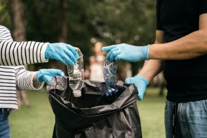 Hands of women and men collect plastic waste for cleaning at the park.